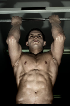 very power athletic guy ,  execute exercise tightening  on horizontal bar, in  sport-hall, glamour...