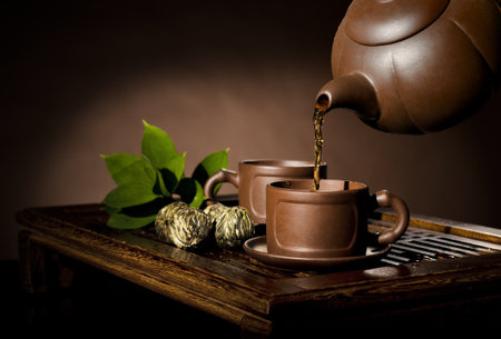 horizontal photo, of the clay teapot tea flow in  cup on brown background,  tea ceremonyの写真素材