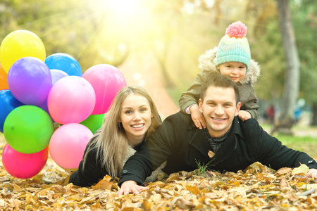 happy family with little child and air-balloons, outing in autumn parkの写真素材