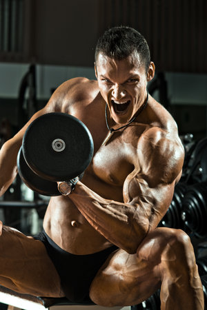 very power athletic guy ,  execute exercise with  dumbbells, on bkack backgroundの写真素材