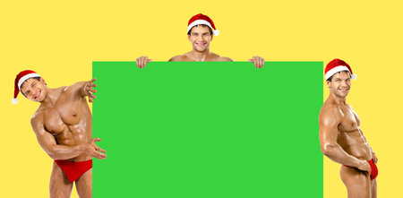 three muscular  bronzed handsome sexy Santa Claus, look out from board and smileの写真素材