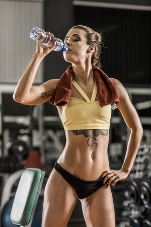 young fitness woman with bottle water in gym, vertical photoの写真素材