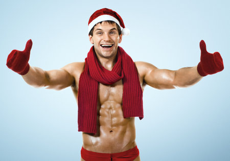 muscular bronzed hfitness Santa Claus; in muffler on blue  background,  smileの写真素材