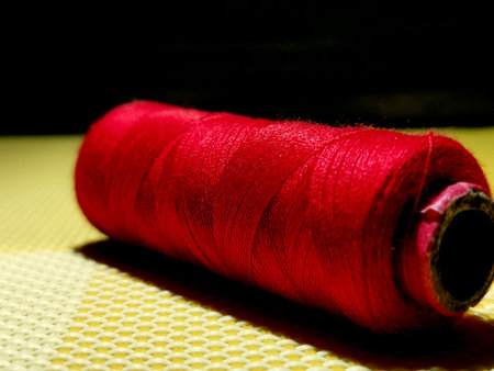 Red color sewing thread with dark background.の写真素材