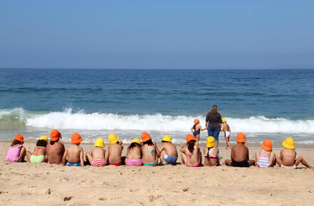 Cute children on the beach in the vivid swimming suits and funny multi coloured hats の写真素材