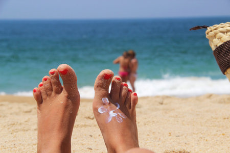 Female feet with sun pictured by cream の写真素材