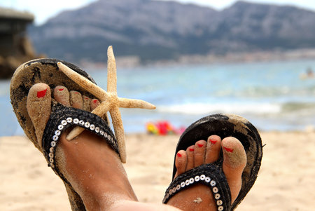 Beautiful female feet on the beach decorated with the starfish 