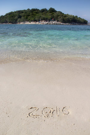 Handwriting inscription 2016 on the beach with clean blue water