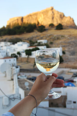 Glass of wine and Greek white houses Lindos, Rhodes, Greeceの写真素材