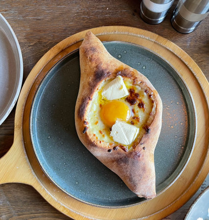 Delicious Georgian khachapuri adjaruli with fresh egg and cheeseの写真素材