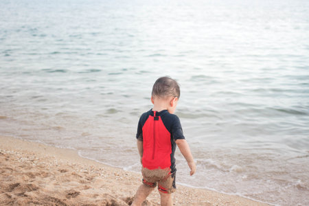 Boy in red swimming suit playing on the sea shore.の写真素材