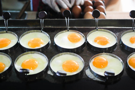Fried egg in row pattern with the circle mold on hot panの写真素材