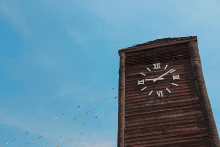 Wooden clock tower with blue sky blackground.の写真素材