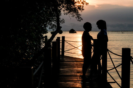 Shadow of couple stand on bridge in the sea.の写真素材