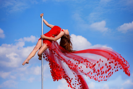 Sportish smiling girl makes acrobatic element at pole danceの写真素材