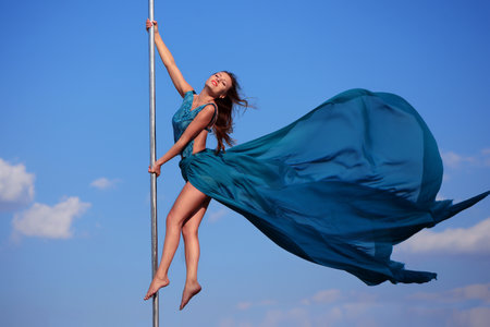 Sportish smiling girl makes acrobatic element at pole danceの写真素材