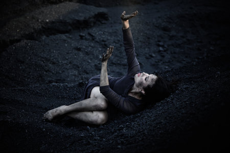 Beautiful sad girl on a mound of coalの写真素材