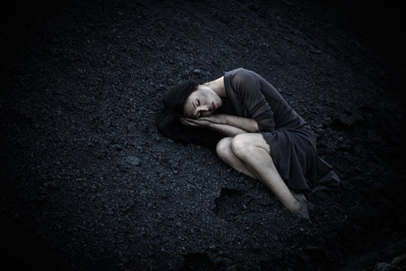 Beautiful sad girl on a mound of coalの写真素材