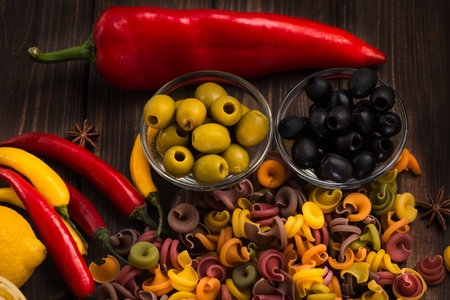 Colorful pasta in raw form with olives and olives and sweet red pepper. Ingredients of Italian dishes. Close-up.の写真素材
