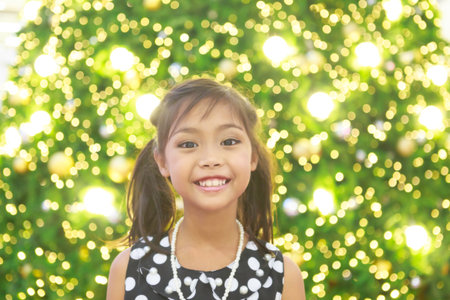A cute asian girl in black dress with white spot and tie hair enjoys with Christmas lightsの写真素材