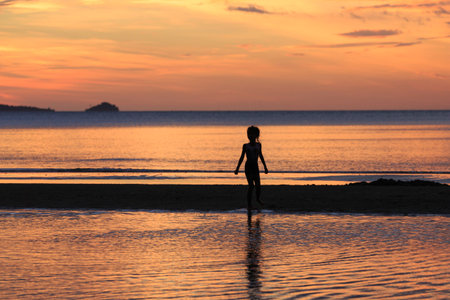 the silhouette photo of asian girl enjoy on the beach with colorful sea in sunriseの写真素材