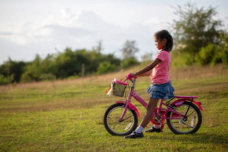 A female schoolchild fun with bicycle in the park.の写真素材