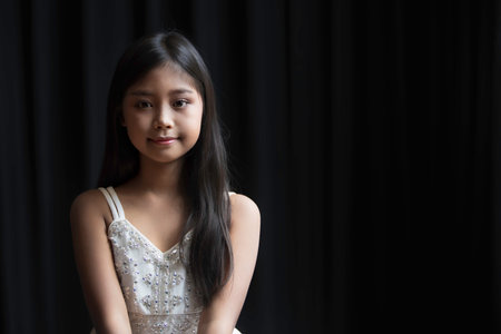 A portrait of a cute, elementary school female  with long hair wearing an evening dress and makeup for a partyの写真素材