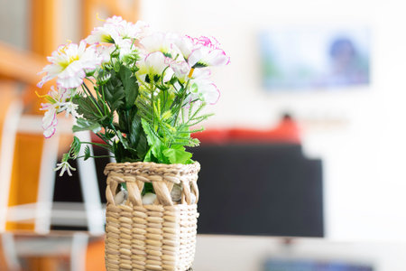 Artificial flowers are in a basket made of wickerwork, used as a beautiful interior decoration of the house.の写真素材