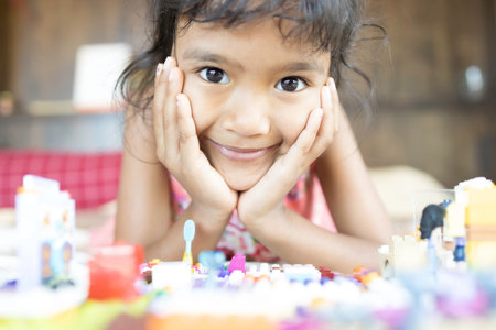 An Asian girl is enjoying playing with a plastic brick in the bed in her bedroom.の写真素材