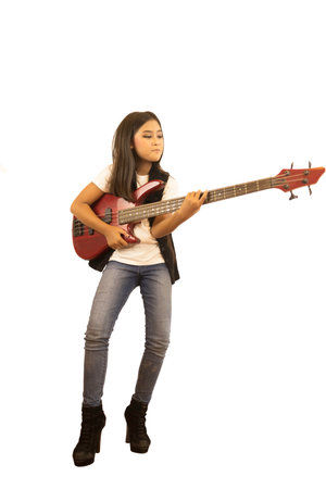 A cute Asian girl with long hair is playing joyfully red electric bass guitar. An isolated image...