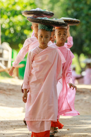 Bagan/Myanmar-October 4th 2019: A Burmese female novice walks to donate food in the morning by placing a basket on the head.のeditorial素材