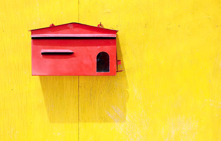Red mail box on old yellow wooden doorの写真素材