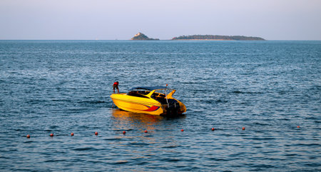 yellow motor boat on the sea on the backdrop of the islandの写真素材