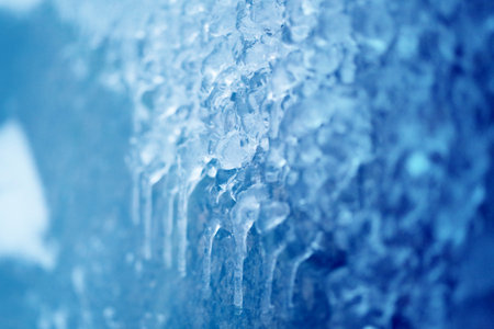 Photo background of bright icicles and ice floes on the fences near the river