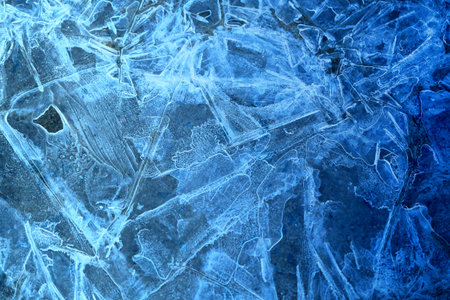 Photo background bright blue frosted thin ice with cracks in the spring