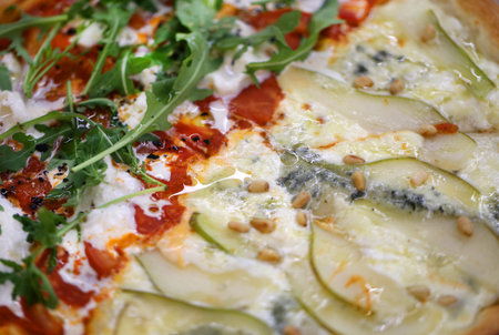 Macro photo of delicious pizza with pear and cheese on a plate in a restaurantの写真素材