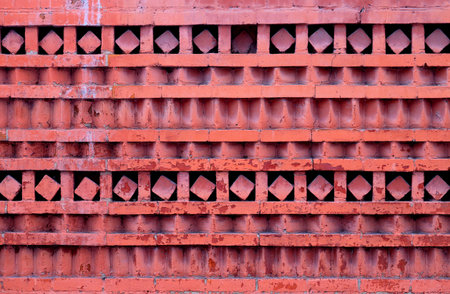 Macro photo of a red ornamental brick wall with different geometric patterns.