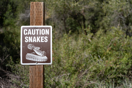 Snake caution sign on wooden post urging visitors to be aware of snake danger.の写真素材