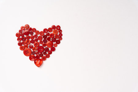 Red Plastic Buttons Arranged in a Heart Shape Isolated on a White Background