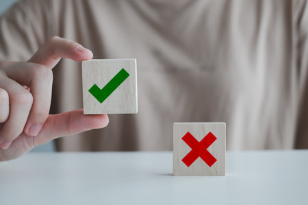 Woman hand pick correct check mark on wooden cube with cross symbol stand on table for true or false changing mindset or way of adapting to change leader and transform quiz answer and poll concept.の写真素材