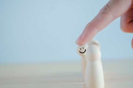 Outstanding talent stand out from the crowd and different concept. Hand touching smile wooden figure from group of crowd. business management and human development concept.の写真素材