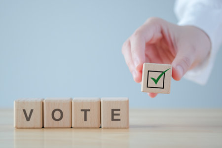 Elections and Voting concept. Hand holding check mark on wooden block with VOTE text on cube blocks