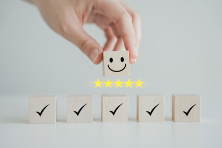 Hand holding smile happy face with 5 star and check mark on wooden block. Feedback rating and...