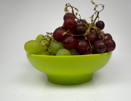 Fresh red and green grapes in a bowl isolated on pink background. Selective focus on the fresh red and green grapes.の写真素材