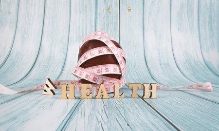Fitness, Healthy Concept. Red apple with measuring tape isolated on blue background . Diet. Dietary nutrition. Text health replacing wealth. Selective focus.の写真素材