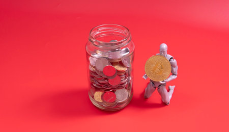 Bitcoin Cryptocurrency. Digital Currency of The Future. Selective focus of a doll on the knee holding bitcoin replica.for saving on the botlle of coinの写真素材