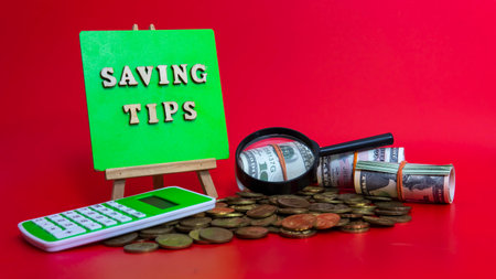 Money saving tips concept. Selective focus on the green board  with a text saving tips. How to save money fro holiday, paying loan or investment conceptの写真素材