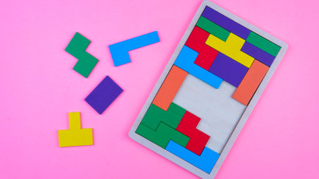 Selective focus of a colorful wooden puzzle on a pink background. Concept of decision making...