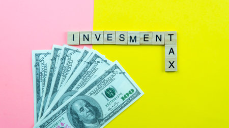 Investment Tax Concept. Selective focus on a fake money and a wood tiles on a yellow and pin backgroundの写真素材