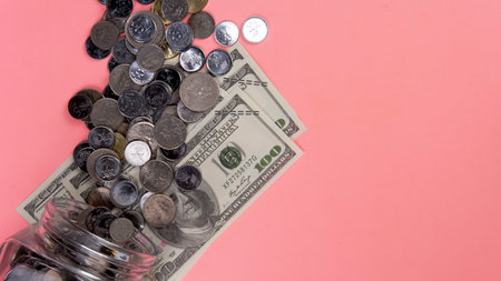 Saving or Econonomy or Business Concept. Selective fous on coins and fake money on a pink backgroundの写真素材
